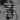 Blurred black and white close-up of a dried autumn leaf on a branch. White uppercase text overlays describe the scent of spiced maple and woodsmoke—evoking seasonal stillness and warmth.