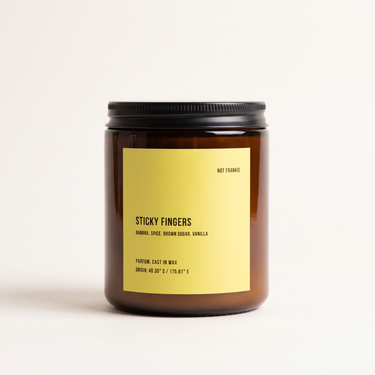 Not Frankie Sticky Fingers soy candle in amber glass with yellow label featuring ripe banana, spice, brown sugar and vanilla fragrance.