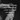 Black and white photo of hands reaching across a dark background, blurred for softness. White overlay text reads: "ROSES PAST THEIR PRIME / PETALS ON COLD TILES / A SCENT THAT LINGERS / LIKE SOMETHING FORGOTTEN." The image evokes intimacy, decay, and nostalgic romance.